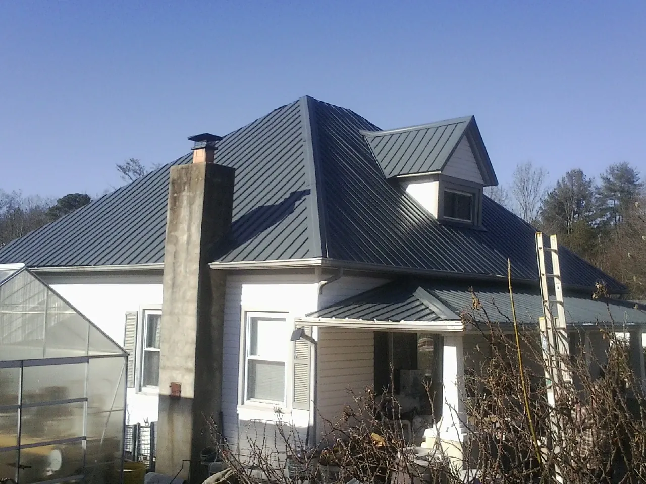 Dark blue standing seam metal roof on a white farmhouse with dormer — Slate & Tile Roof Repair by Roofing Brothers in Lucerne Valley