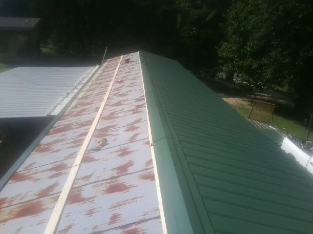 Old rusted panels beside newly installed green metal roofing — Wind Damage Roof Repair by Roofing Brothers in Lucerne Valley