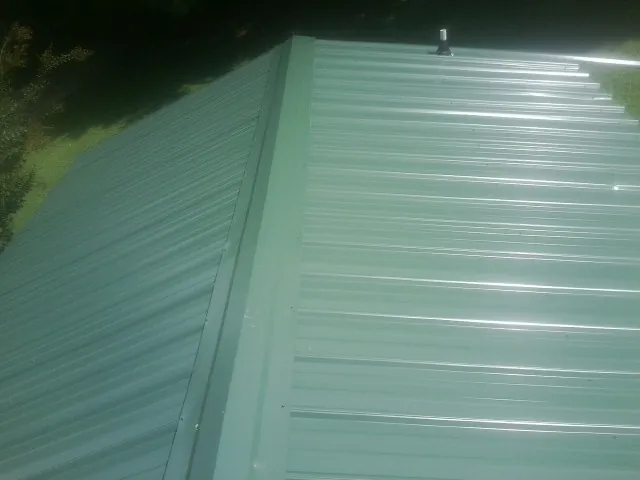 New green metal panels meeting at the ridge of a roof — Flat Roof Repair work by our crew in Lucerne Valley