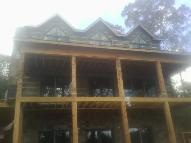 Dormers and porch framing on a large log home under construction — Roof Coating work by our crew in Lucerne Valley