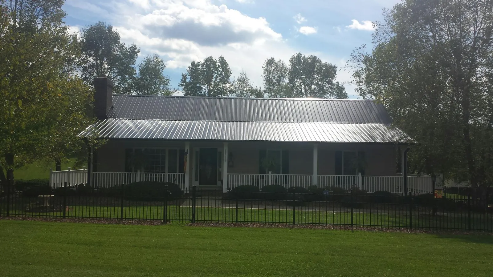 Gray metal roof on a brick ranch with a full width front porch — Gutter Guard Installation work by our crew in Lucerne Valley