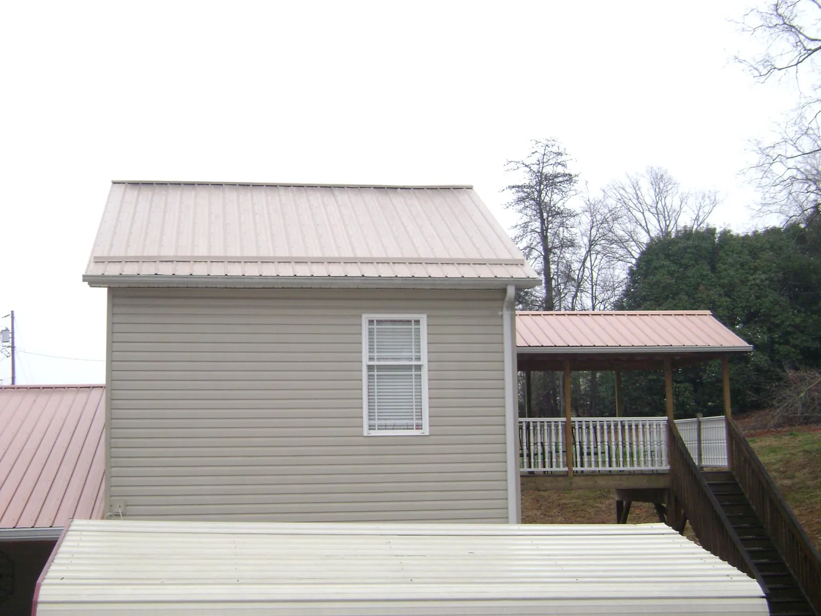 Tan metal roofs on a two story addition and attached porch, from a Roof Replacement job in Lucerne Valley