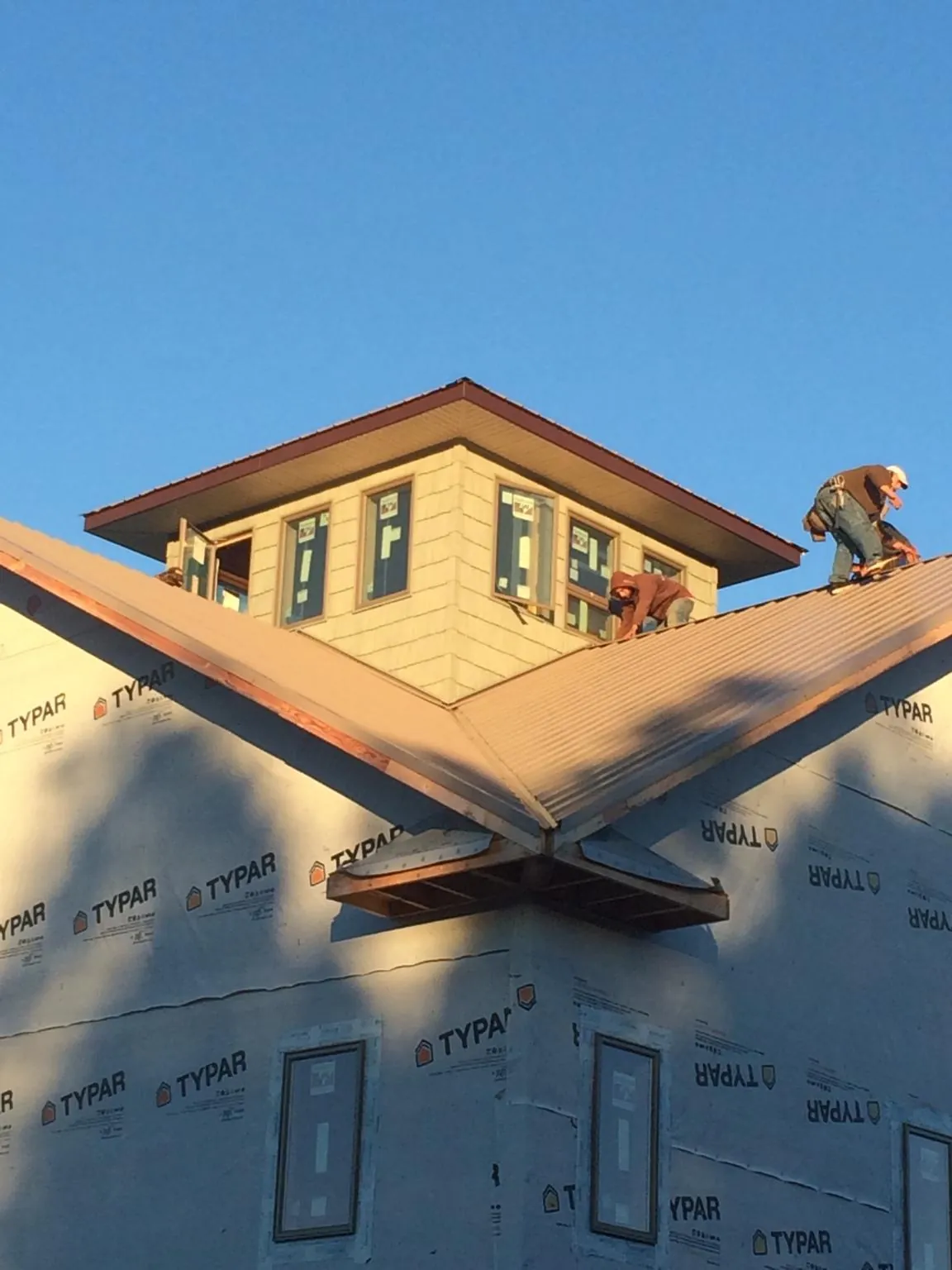 Roofers working around a rooftop cupola on a new metal roof at sunset — Roof Waterproofing in Lucerne Valley by Roofing Brothers